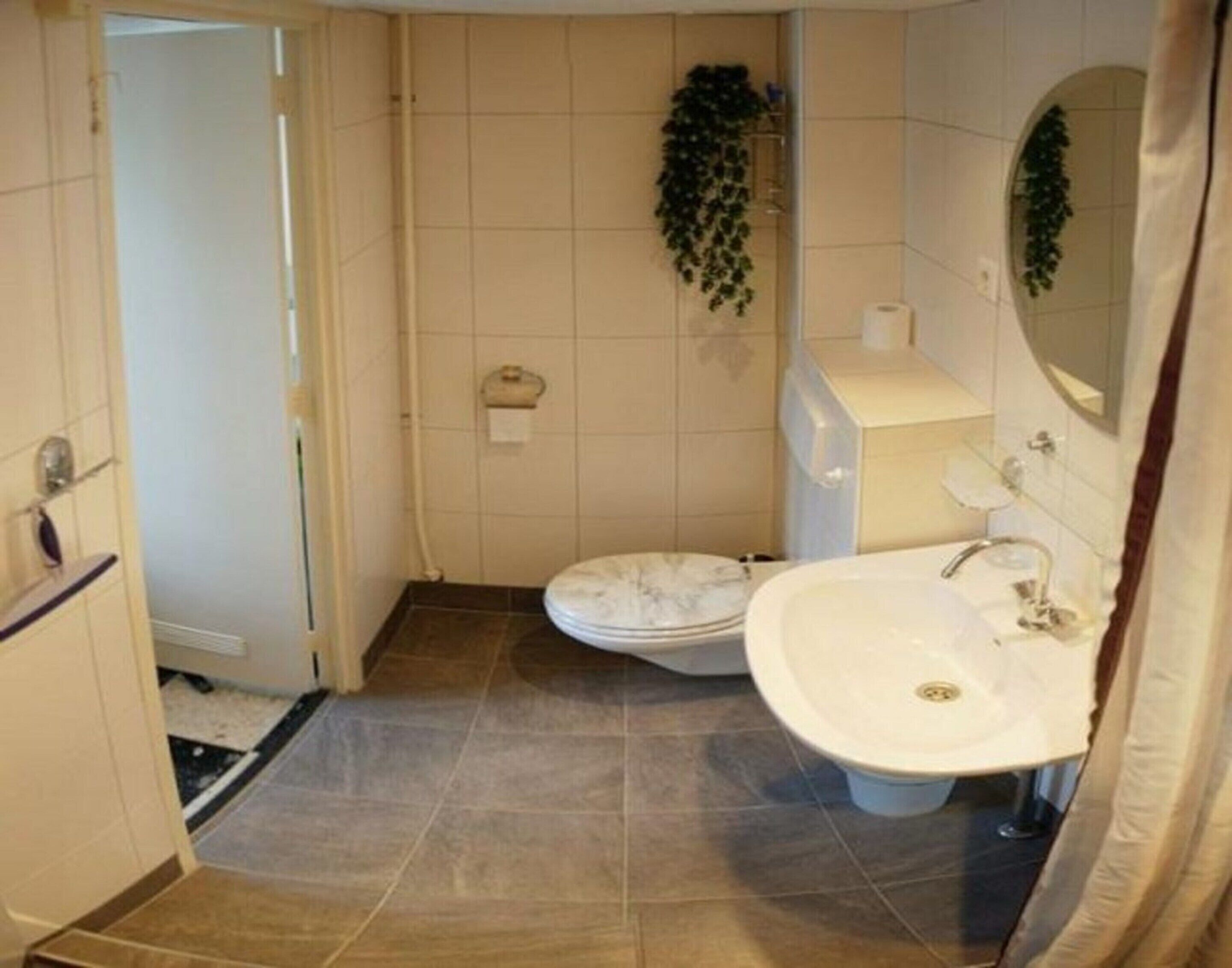 Une salle de bain avec des toilettes, un lavabo et une douche.