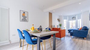 Ein modernes Wohnzimmer mit Essbereich, ausgestattet mit einer Couch, Sesseln und einem für das Essen gedeckten Tisch.