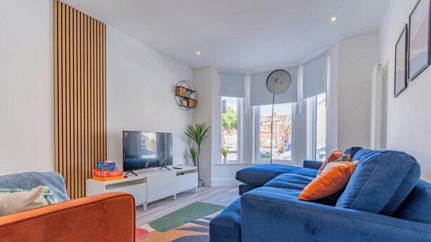 Ein modernes Wohnzimmer mit einem blauen Sofa, einem Fernseher und einem weißen Schrank.