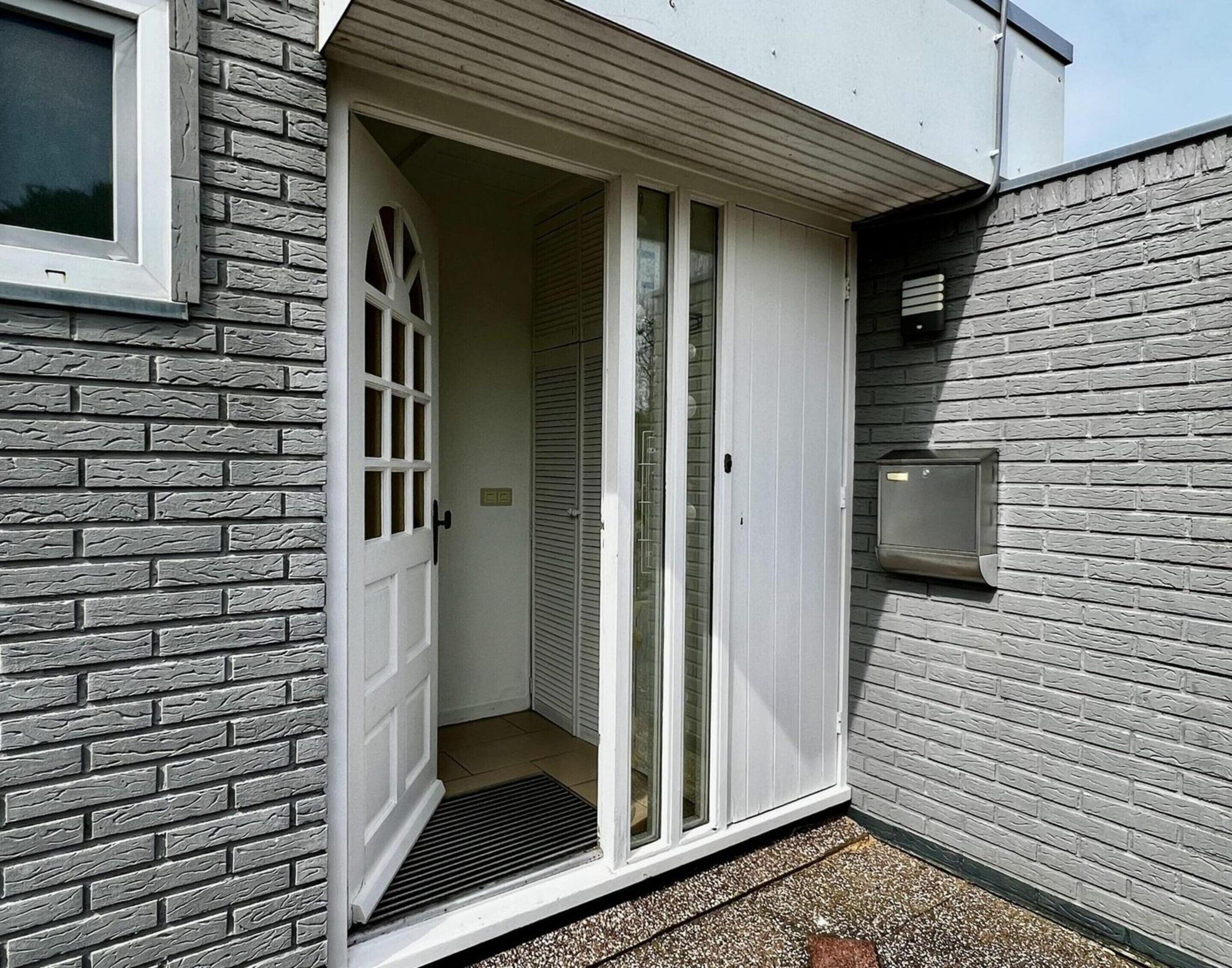 A narrow entryway with a white door, a small window, and a mailbox on the wall.