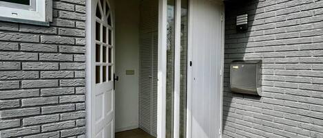A narrow entryway with a white door, a small window, and a mailbox on the wall.