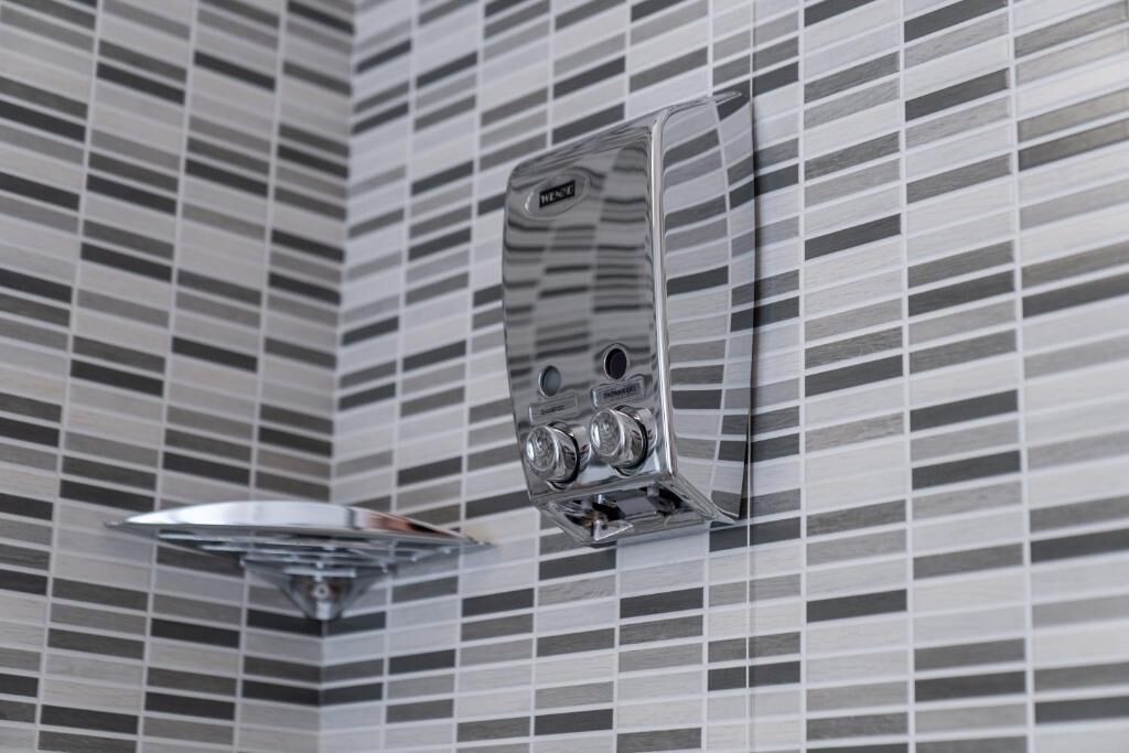 A bathroom with a tiled wall and a chrome showerhead.