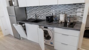 A modern kitchen with a built-in washing machine, a sink, and a microwave. - DOLCE NOTTE APARTMENTS (Verona)