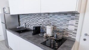 A modern kitchen with a black countertop, stainless steel appliances, and a tiled backsplash. - DOLCE NOTTE APARTMENTS (Verona)
