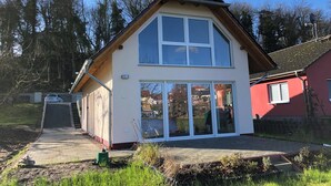 Ein zweistöckiges Haus mit großem Schiebeglaseingang, einem Ziegeldach und einer sichtbaren Satellitenschüssel.