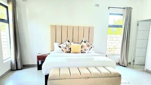 Un dormitorio moderno con una cama grande, un cabecero de madera y un banco al pie de la cama.
