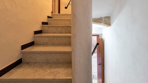A staircase with marble steps and a handrail, leading to a door with a stone accent. - Sardinia Re - Maiorca 13 (Alghero)