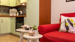 A compact kitchen with a microwave, oven, and small table with a plant and decorative items. - Sardinia Re - Maiorca 13 (Alghero)