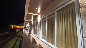 A hotel corridor with large windows and a well-lit exterior.