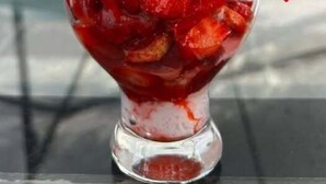 A dessert with whipped cream and strawberries in a clear glass cup.