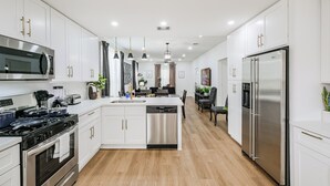 Una cocina moderna con armarios blancos, electrodomésticos de acero inoxidable y una isla central.
