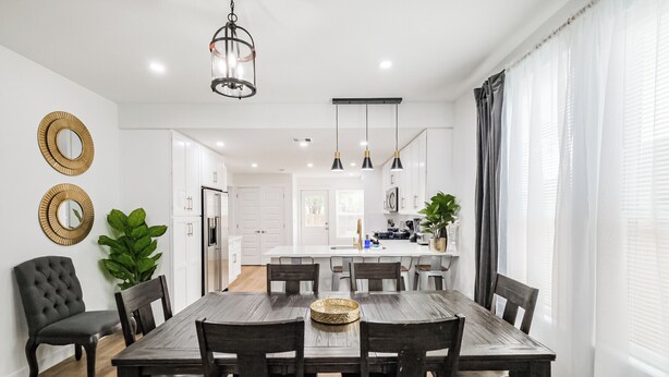 Una cocina moderna con armarios blancos, una isla central e iluminación colgante.