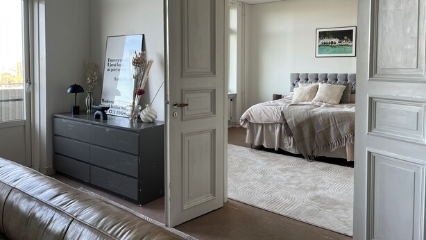 Een slaapkamer met een bed, een kaptafel en een deur naar een andere kamer.