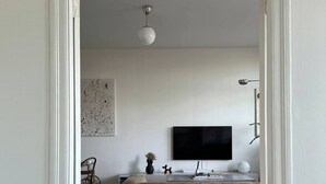 Een moderne woonkamer met een grote bruine bank, een flatscreen televisie en een minimalistische inrichting.