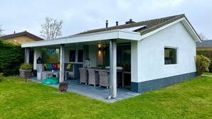 A modern house with a covered patio, a lawn, and a garden. - Lovely Holiday Bungalow With Garden (Sint Maartensvlotbrug)