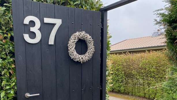 A black wooden door with the number 37, a metal handle, and a decorative wreath. - Lovely Holiday Bungalow With Garden (Sint Maartensvlotbrug)