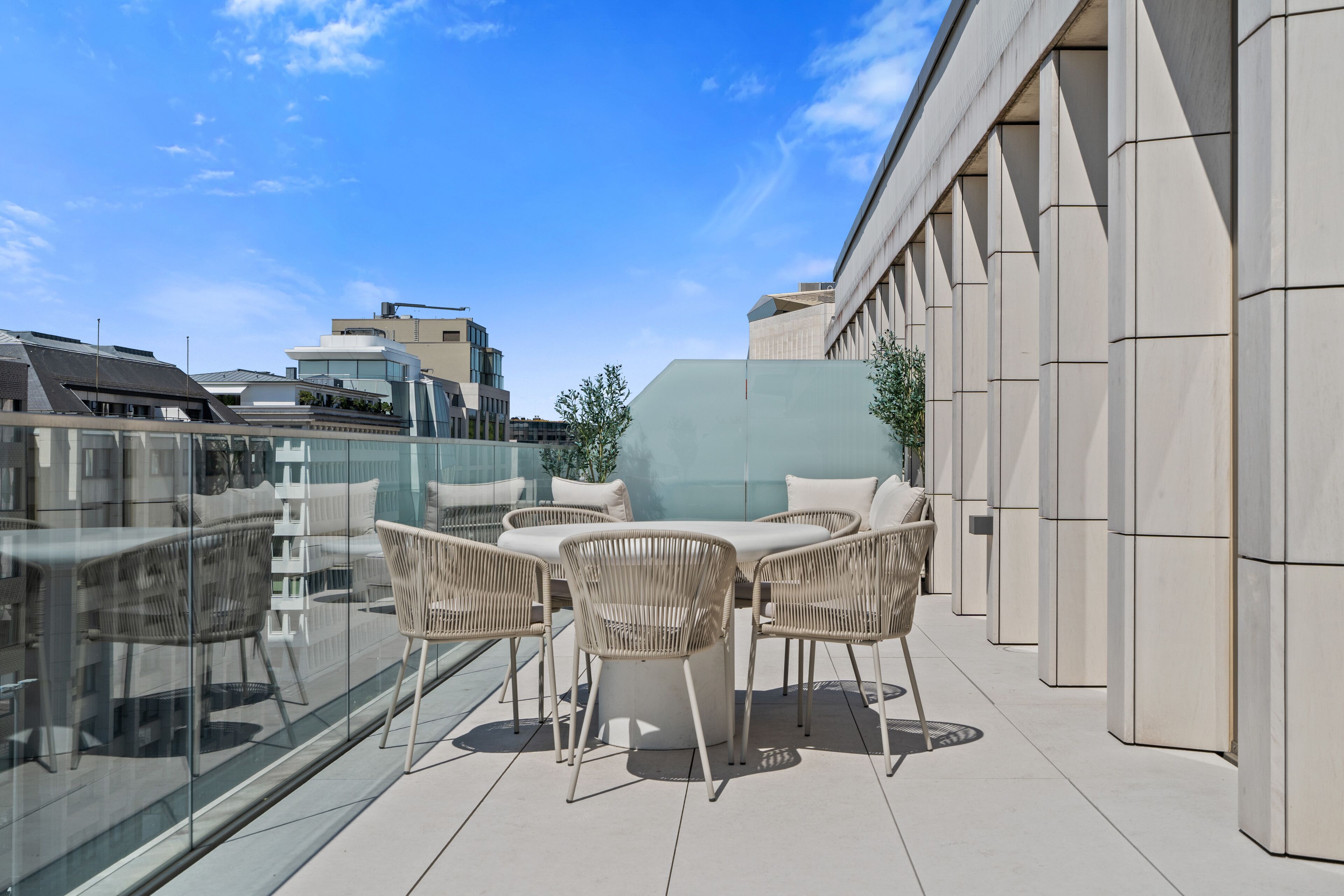 A rooftop terrace with outdoor seating and a glass balustrade.