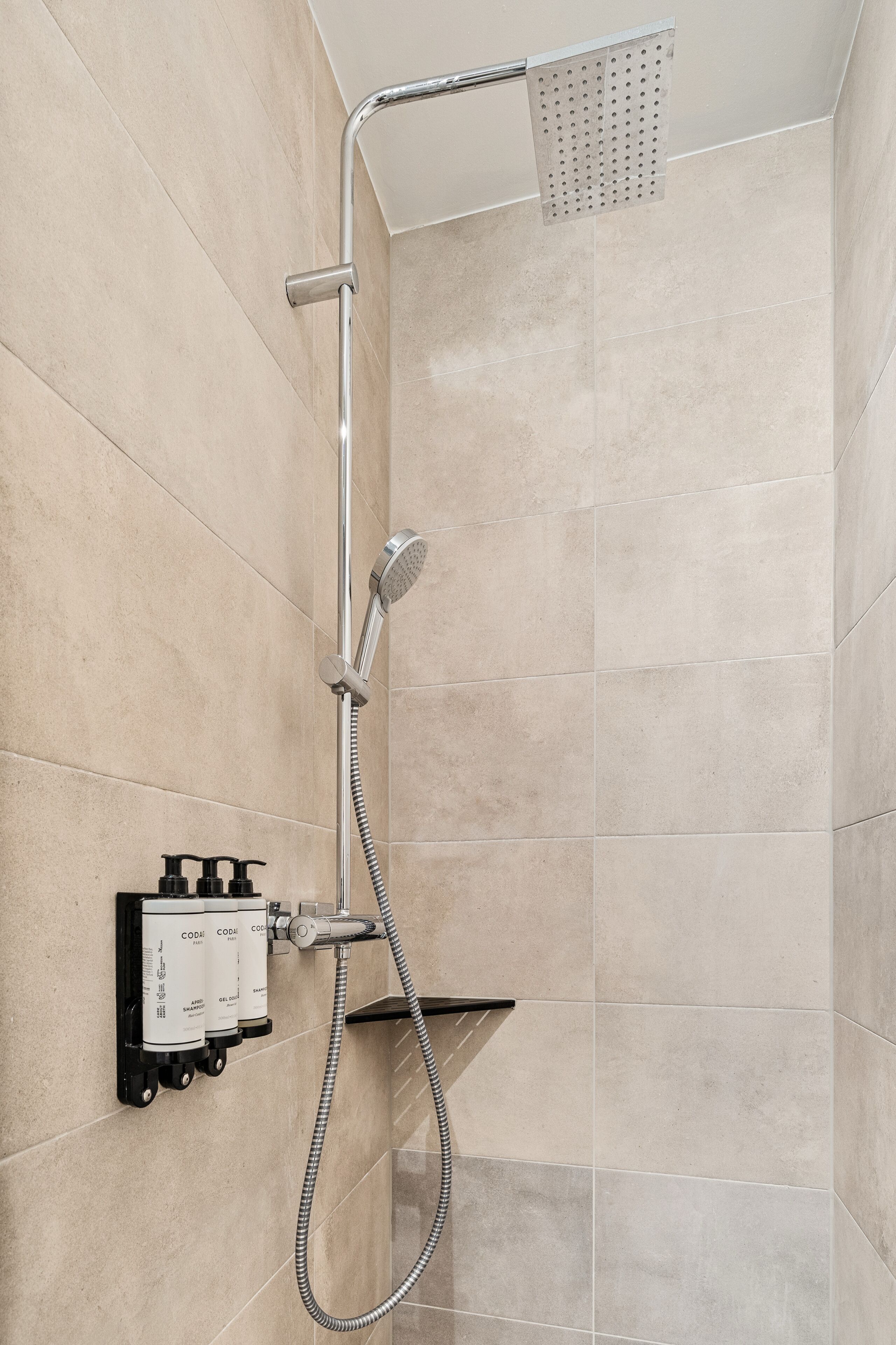 Une douche équipée d’un pommeau de douche à main, d’un panneau de commande mural et d’un flexible de douche à main.