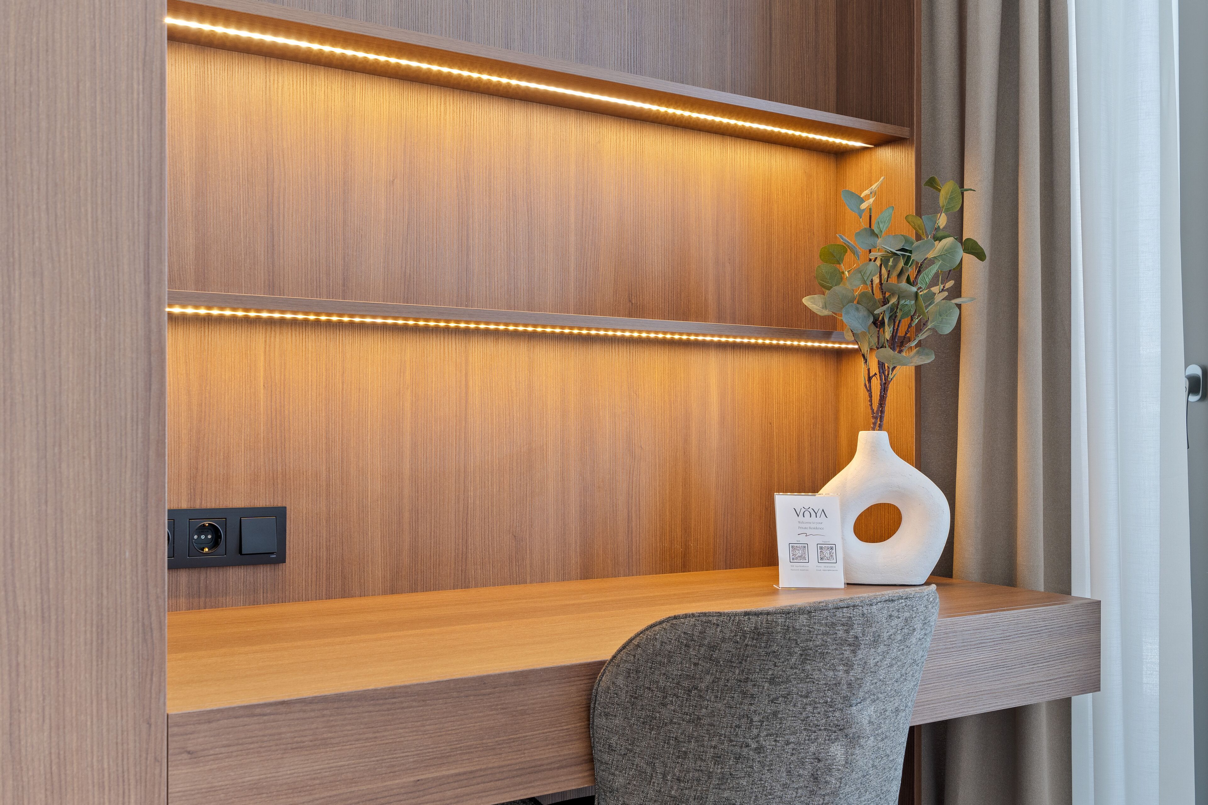 A modern desk with built-in lighting, a vase with a plant, and a sign.