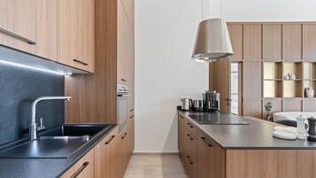 Una cocina moderna con armarios de madera, encimera negra y lámpara colgante.