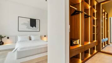 Un dormitorio moderno con una cama grande, una mesita de noche, un cuadro abstracto colgado en la pared y un armario de madera con iluminación integrada.
