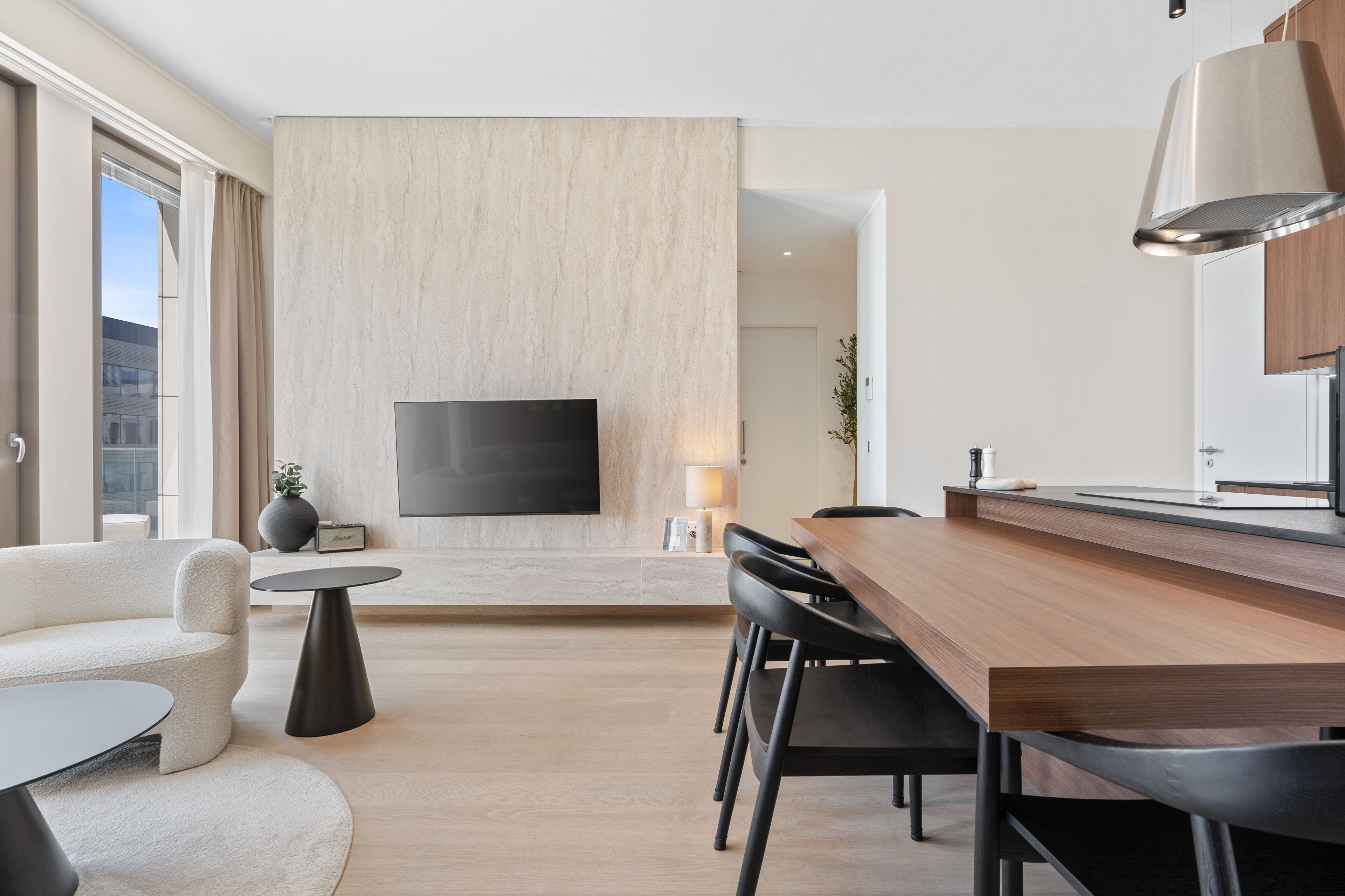 A modern living room with a flat-screen TV, a wooden dining table, and a sofa.
