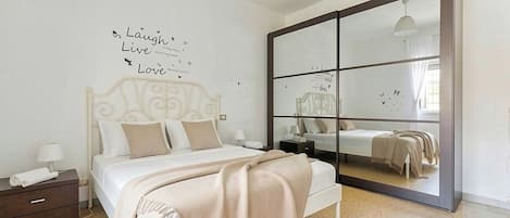 A bedroom with a bed, a nightstand, a dresser, a large mirror, and a wall with motivational text.