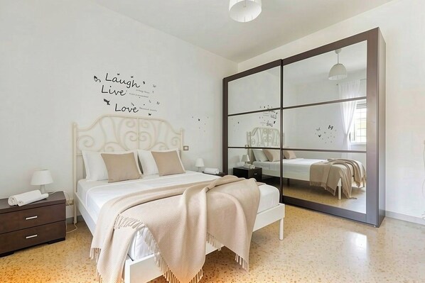 A bedroom with a bed, a nightstand, a dresser, a large mirror, and a wall with motivational text.