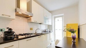 Una cocina moderna con armarios blancos, una estufa a gas y un lavamanos. Hay un florero con flores en la encimera.
