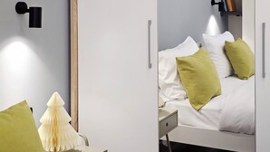 A modern bedroom with a bed, bedside table, lamp, and a painting on the wall.