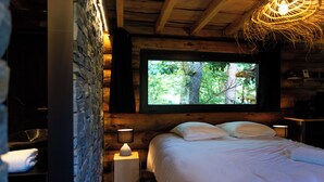 Een gezellige kamer met een bed, een televisie en een stenen muur.
