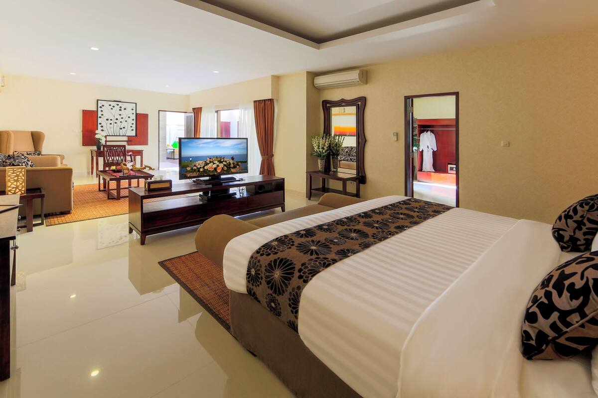 Habitación de hotel con una cama grande, televisión, escritorio y zona de estar.