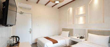 A hotel room with two beds, a bedside table, a TV, and a coffee maker.