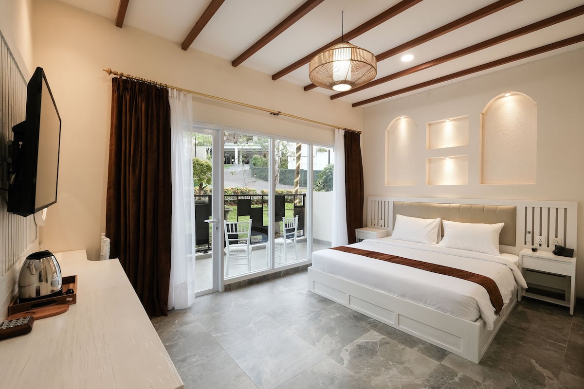 Un dormitorio con una cama grande, un televisor montado en la pared y un ventanal corredero que da a un espacio al aire libre.