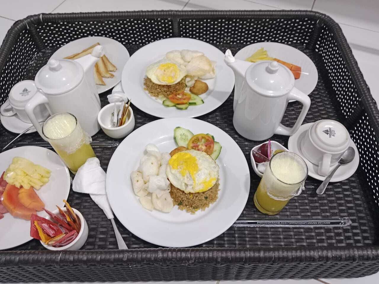 Ein Tablett mit verschiedenen Frühstücksleckereien, darunter gebratenem Reis, Eiern und Obst.
