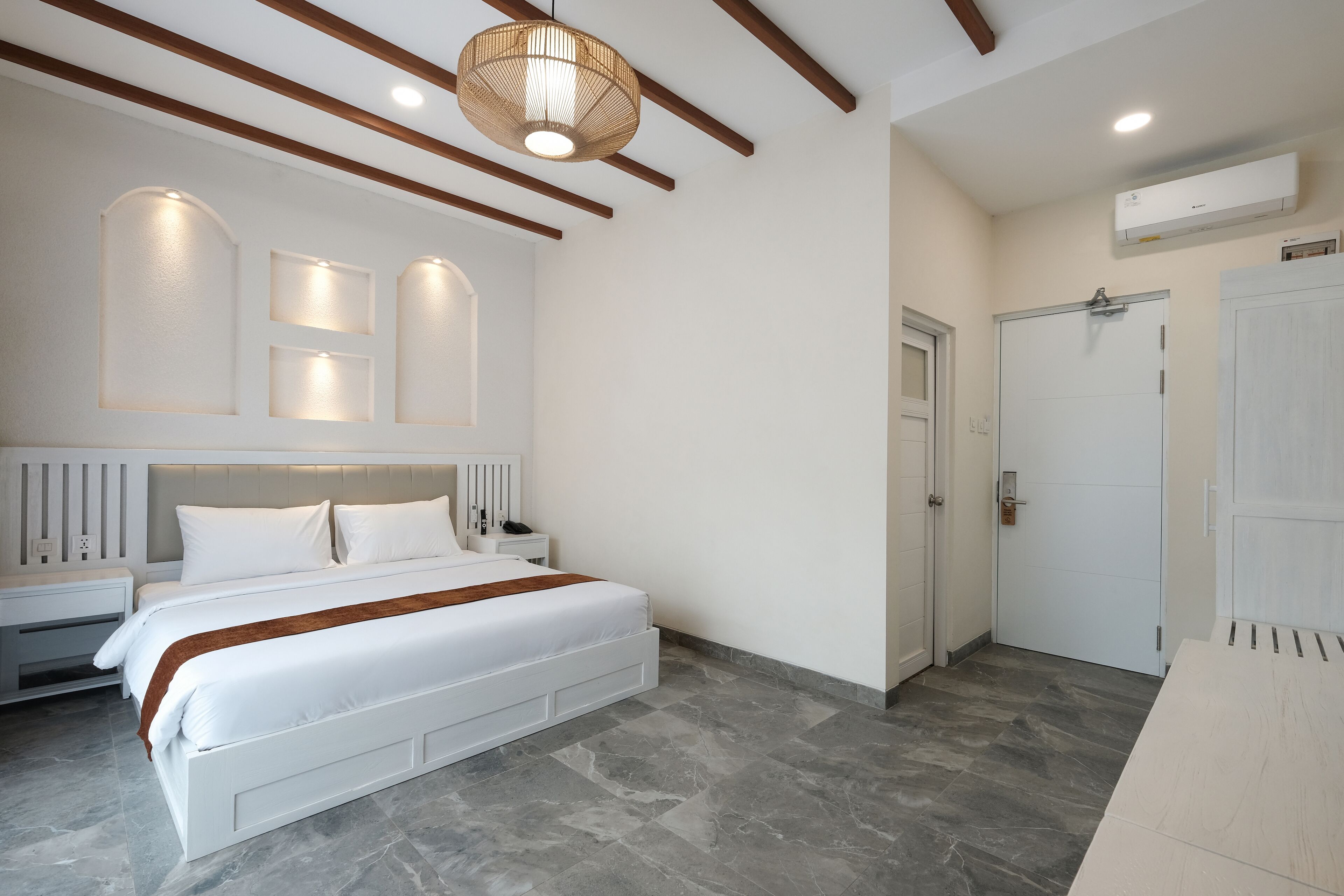 A bedroom with a large bed, bedside tables, a ceiling light fixture, and a door.