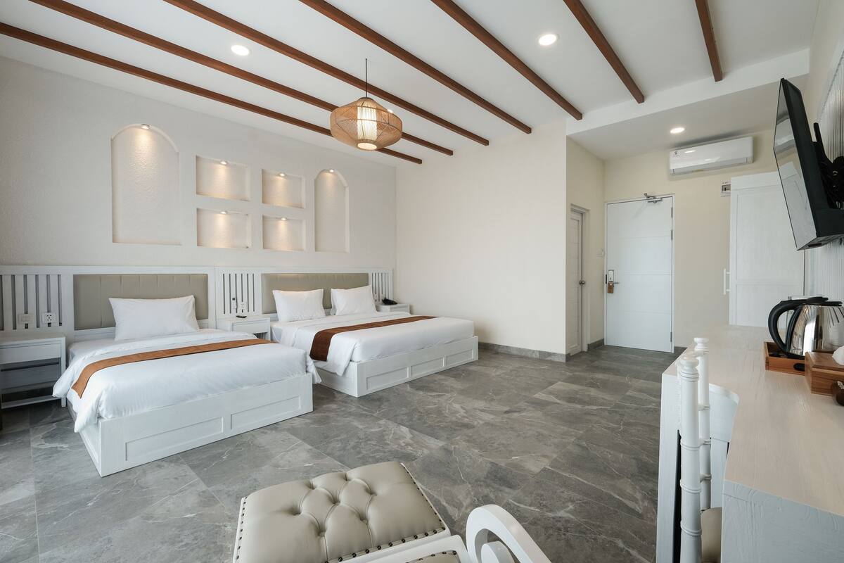 Una habitación de hotel moderna con dos camas, una zona de estar y una kitchenette.