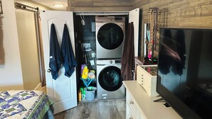A compact laundry room with a washing machine, dryer, and a television.