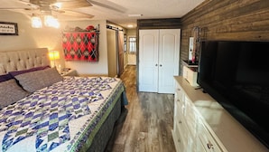 A bedroom with a bed, a ceiling fan, a TV, a dresser, and a wardrobe.