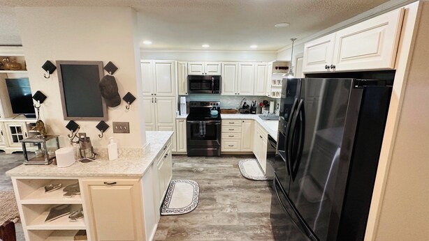 A kitchen with white cabinets, a black refrigerator, and a microwave.