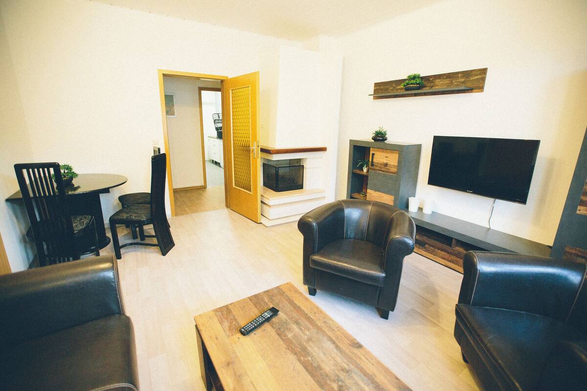 A living room with a fireplace, a television, and leather furniture.