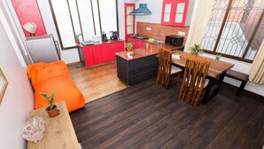 Un espacio habitable compacto con kitchenette, comedor y zona de estar con sillón de peluche.