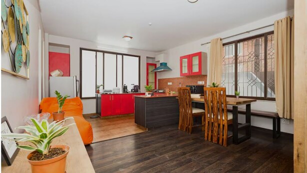Una cocina moderna con armarios rojos, una isla central y un comedor con una silla y mesa de madera.