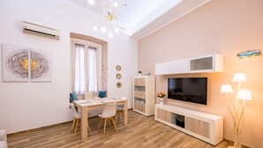 Ein modernes Wohnzimmer mit Essbereich, einem Flachbildfernseher und einer weißen Kommode.