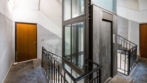 Ein modernes Interieur mit einem Glaselevator, einer Holztür und einer Treppe mit Metallgeländern.