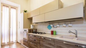 Eine moderne Küche mit Holzschränken, einem Gasherd, einer Spüle und einem Fenster mit Vorhängen.