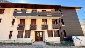 Un edificio de varios pisos con balcones, fachada de madera y entrada protegida por una reja.