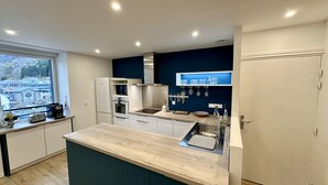 Una cocina moderna con una isla grande, electrodomésticos integrados y vistas a un edificio tradicional.