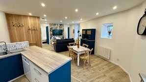 Una cocina moderna con una isla de madera, una zona de comedor con una mesa y sillas, un sofá y una sala de estar con televisor.