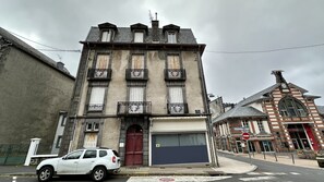 A historic building with a large garage door, a red door, and a white car parked in front.